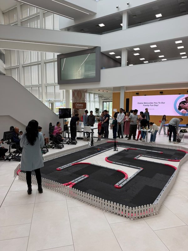 Guests gathered round the FPV RC racing track at Elekta's family fun day, with the welcome screen behind